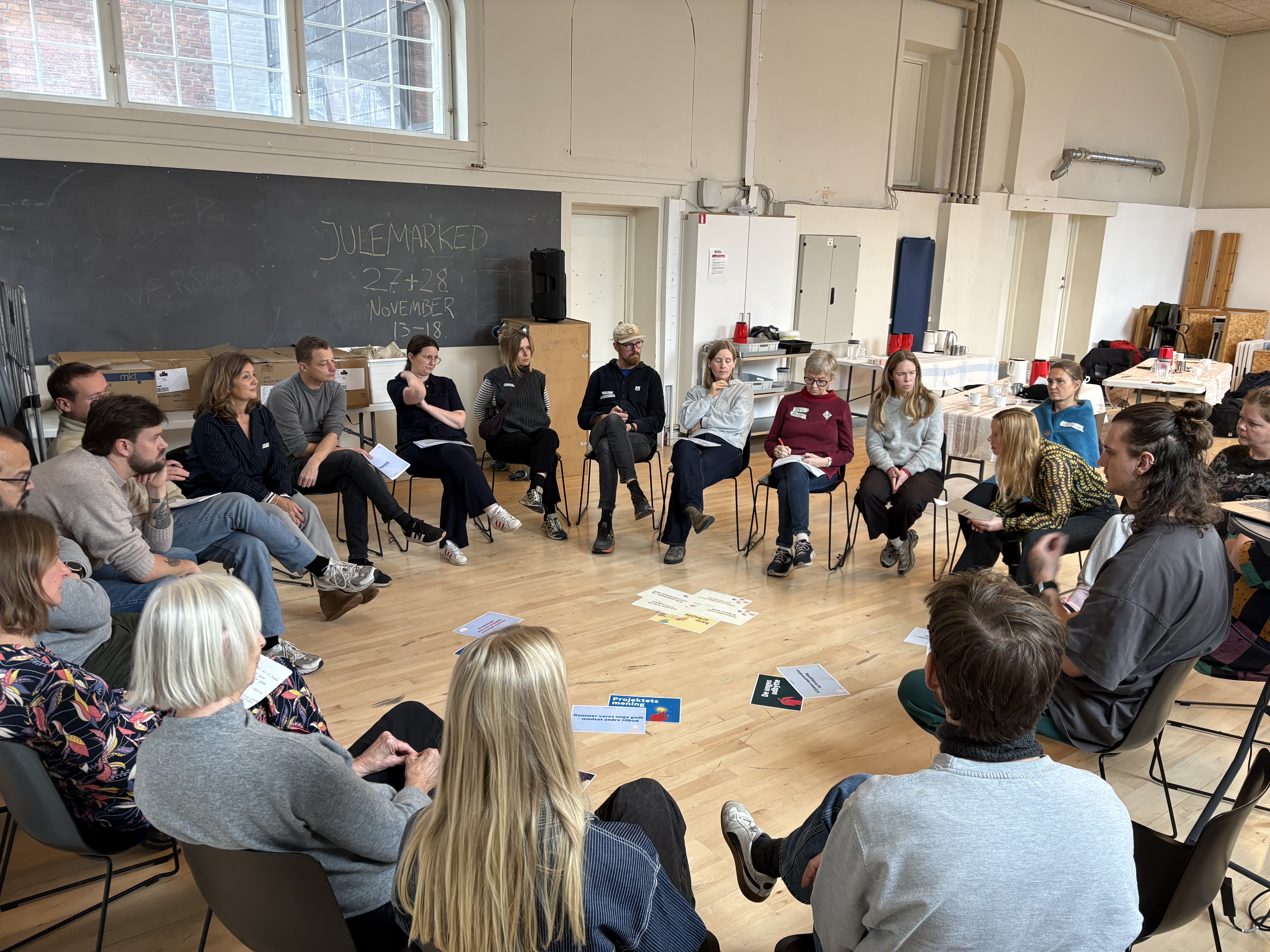 Gruppe af mennesker sidder i rundkreds og taler sammen om læring